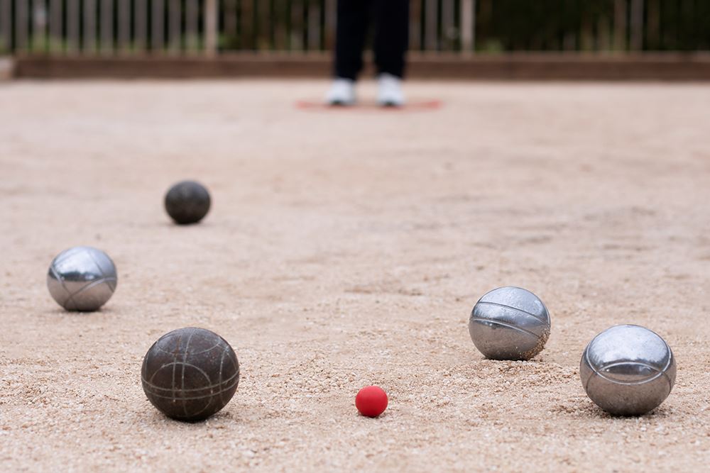 Friends playing Bocce Ball on a sand court