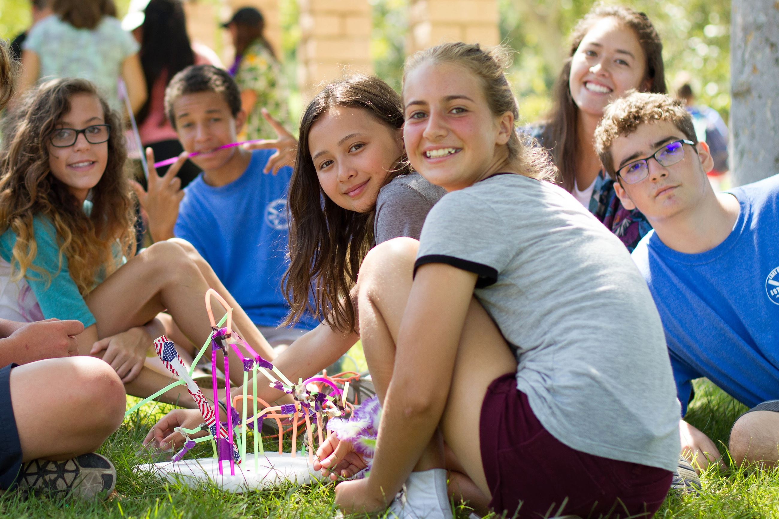 Group of Teens Sitting on Ground Smiling for Photo